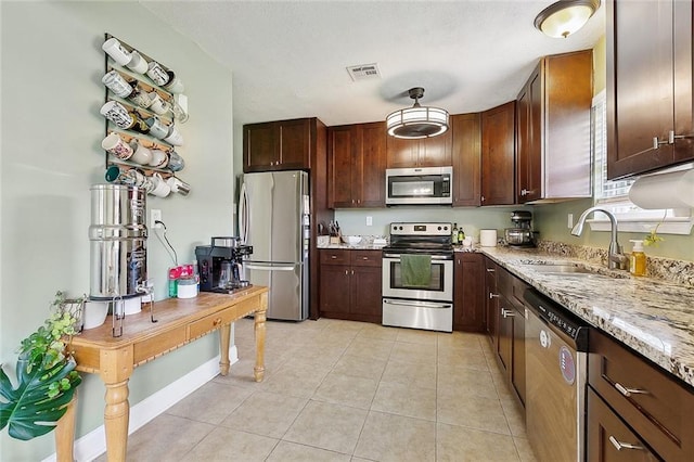 kitchen with visible vents, light stone counters, a sink, appliances with stainless steel finishes, and light tile patterned floors