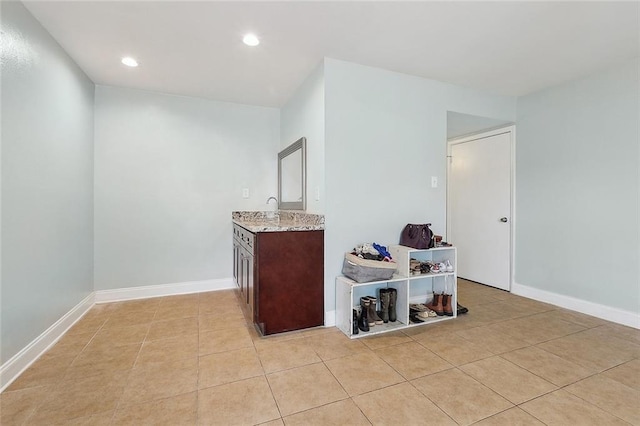 interior space with light tile patterned floors, baseboards, recessed lighting, and a sink