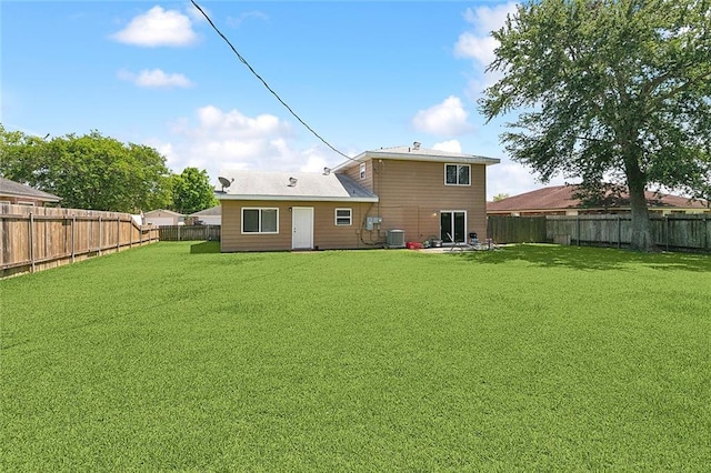 back of house with a fenced backyard, central AC, and a yard