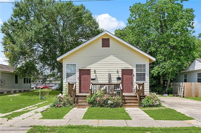 bungalow-style house with fence, driveway, and a front lawn