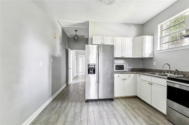 kitchen featuring a sink, white cabinetry, appliances with stainless steel finishes, and light wood-style flooring