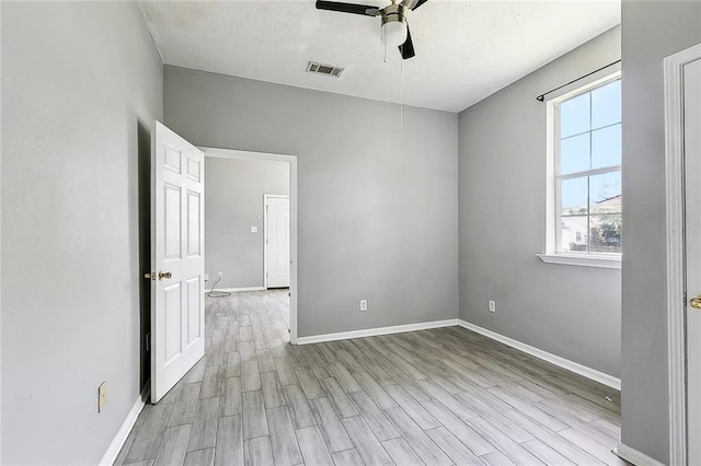 spare room with baseboards, a ceiling fan, wood finished floors, and visible vents