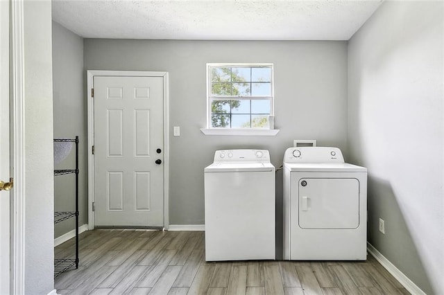 laundry area with laundry area, washer and clothes dryer, light wood finished floors, and baseboards