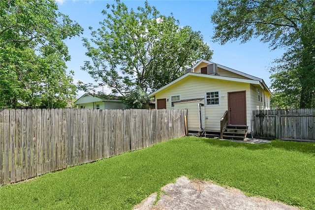 rear view of property featuring a yard, a fenced backyard, and entry steps