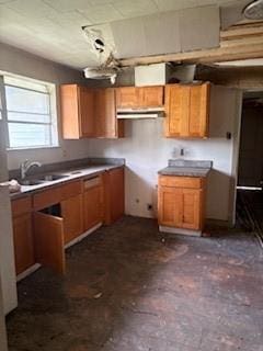 kitchen featuring a sink, brown cabinetry, and under cabinet range hood