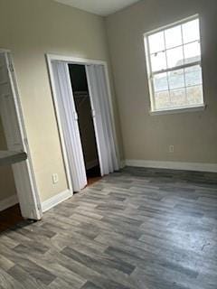 unfurnished bedroom with baseboards, wood finished floors, and a closet