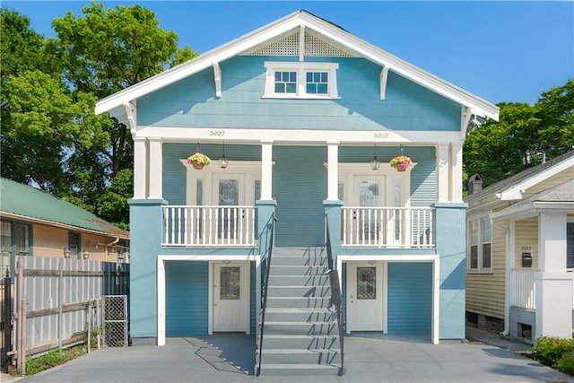 view of front of property with a porch, fence, and stairway