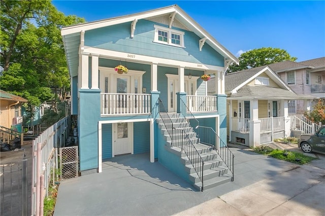 view of front of house featuring covered porch, fence, and stairs
