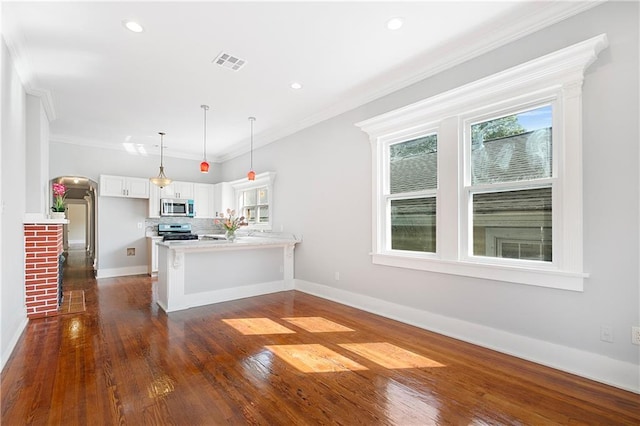 kitchen with stainless steel appliances, white cabinetry, a peninsula, visible vents, and ornamental molding