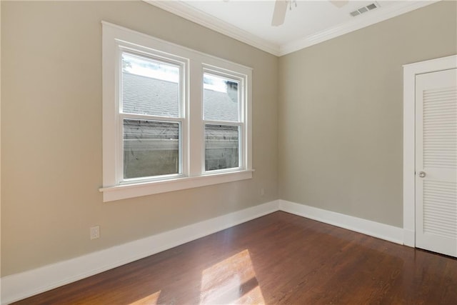spare room featuring crown molding, a ceiling fan, baseboards, dark wood-type flooring, and visible vents