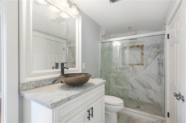 bathroom with vaulted ceiling, a marble finish shower, vanity, and toilet