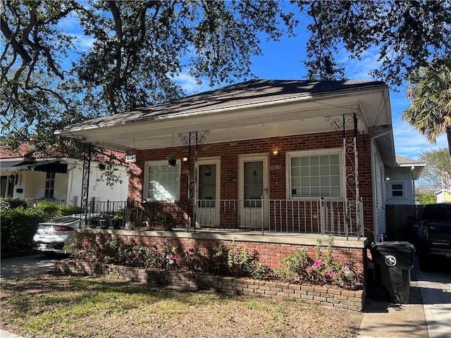 bungalow-style home featuring covered porch and brick siding