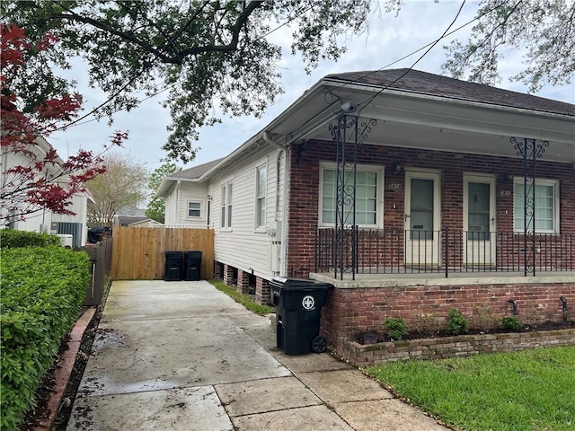 view of home's exterior featuring fence, a porch, and brick siding