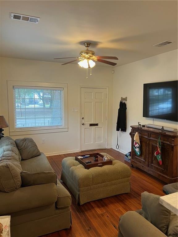 living area with baseboards, a ceiling fan, wood finished floors, and visible vents