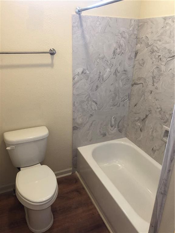 bathroom featuring toilet, wood finished floors, and shower / tub combo with curtain