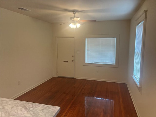 unfurnished room with baseboards, a ceiling fan, hardwood / wood-style floors, and visible vents