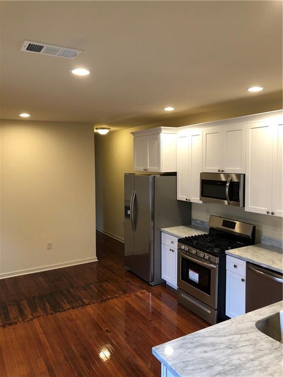 kitchen with visible vents, dark wood-style flooring, baseboards, white cabinets, and appliances with stainless steel finishes