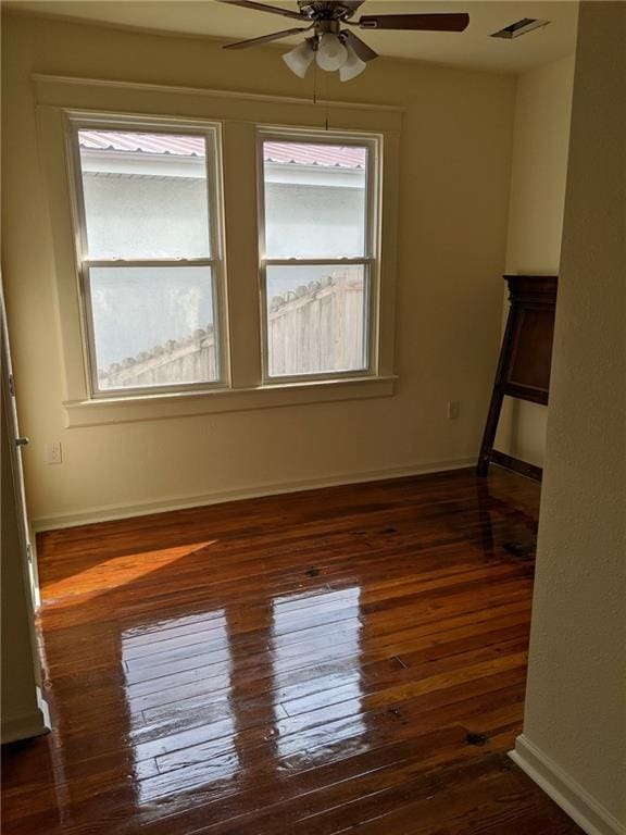spare room featuring a wealth of natural light, a ceiling fan, dark wood finished floors, and visible vents