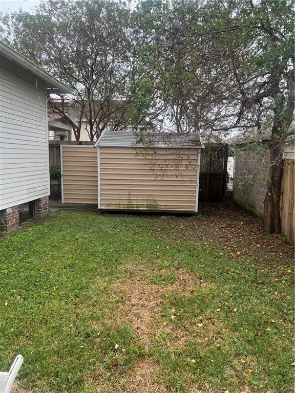 view of yard featuring a fenced backyard, an outdoor structure, and a shed
