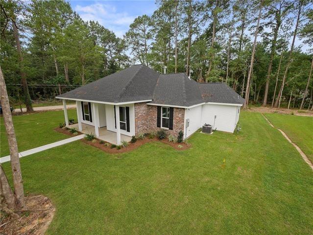 166 Egret St, Covington, LA 70433 - view of front of home featuring cooling unit, a front lawn, a shingled roof, and brick siding