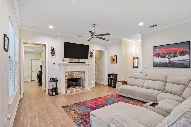 166 Egret St, Covington, LA 70433 - living room with ceiling fan, light wood-style flooring, crown molding, recessed lighting, and a fireplace