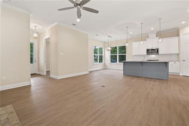 unfurnished living room with recessed lighting, baseboards, crown molding, and wood finished floors