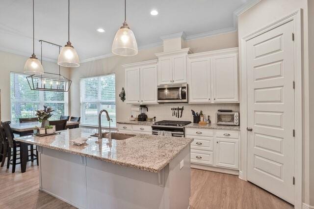 kitchen featuring a sink, appliances with stainless steel finishes, ornamental molding, and white cabinetry