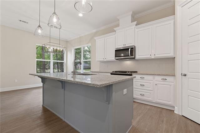 kitchen featuring a sink, ornamental molding, stainless steel microwave, and dark wood finished floors