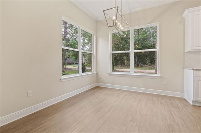 unfurnished dining area with an inviting chandelier, baseboards, crown molding, and light wood-style floors