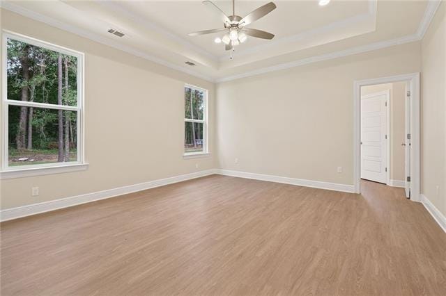 spare room featuring crown molding, a raised ceiling, a ceiling fan, baseboards, and wood finished floors