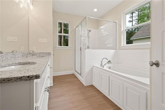 full bath featuring a sink, a garden tub, a shower stall, and wood finished floors