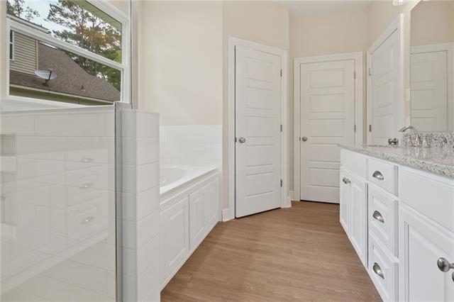 166 Egret St, Covington, LA 70433 - bathroom featuring vanity, a bath, wood finished floors, and a shower with shower door