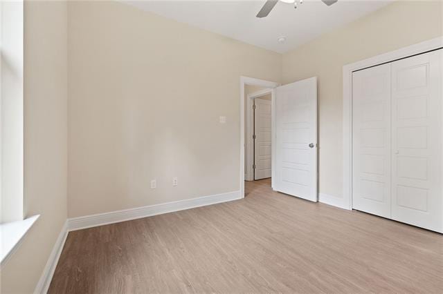 unfurnished bedroom with baseboards, a ceiling fan, a closet, and light wood-style flooring