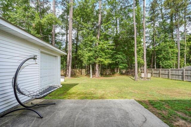 view of yard featuring a fenced backyard, a patio area, and a garage