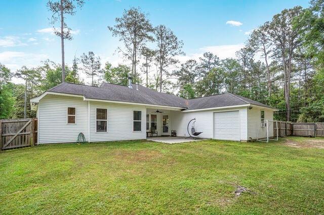 back of house featuring a fenced backyard, a patio, an attached garage, and a lawn