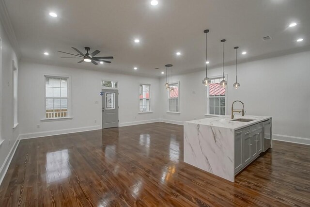 kitchen with a sink, baseboards, a center island with sink, and dark wood-type flooring