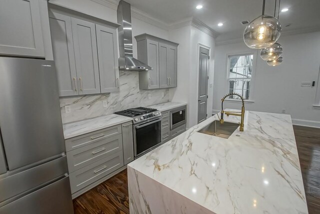 kitchen with ornamental molding, wall chimney range hood, a sink, gray cabinetry, and stainless steel appliances