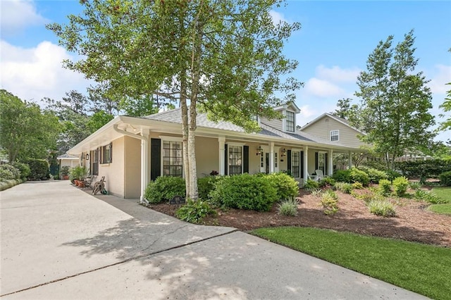 view of front of house featuring stucco siding, a porch, and driveway