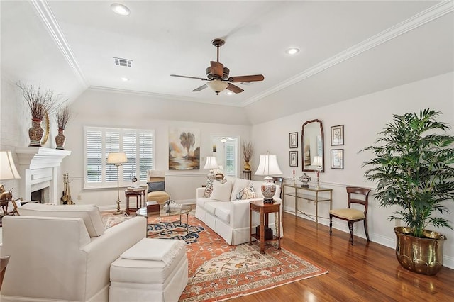living room featuring ceiling fan, visible vents, crown molding, wood finished floors, and baseboards