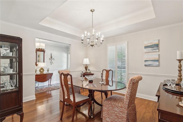dining area with crown molding, a raised ceiling, a notable chandelier, and hardwood / wood-style floors