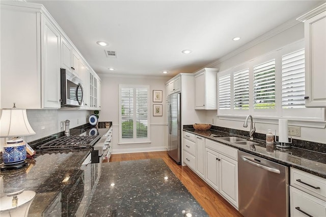 kitchen with a sink, light wood finished floors, stainless steel appliances, white cabinetry, and ornamental molding