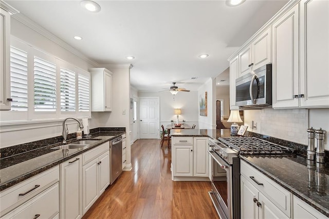 kitchen with a sink, stainless steel appliances, a ceiling fan, recessed lighting, and light wood-type flooring