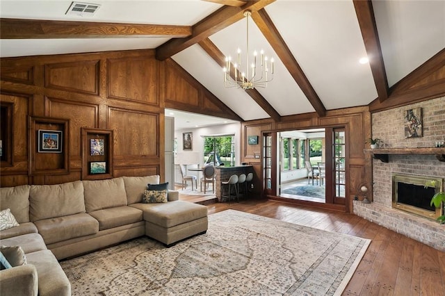 living area with visible vents, beamed ceiling, hardwood / wood-style flooring, and a chandelier