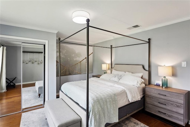 bedroom with crown molding, visible vents, dark wood-style flooring, a closet, and baseboards