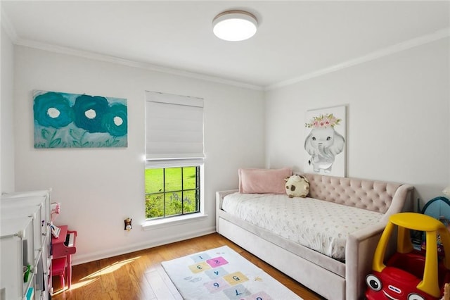 bedroom with crown molding, baseboards, and wood finished floors