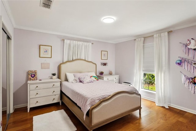 bedroom featuring crown molding, visible vents, a closet, and dark wood-type flooring