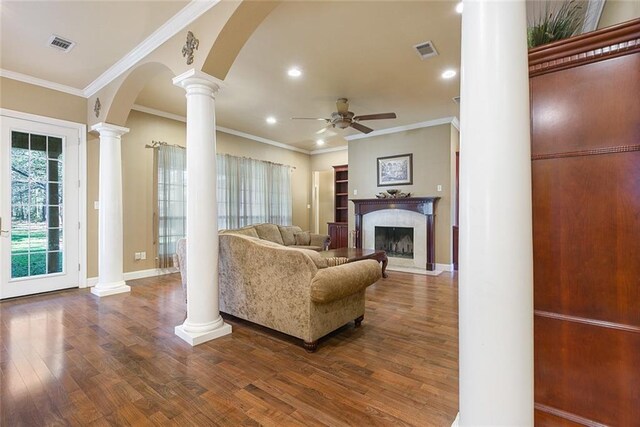 living area with ceiling fan, decorative columns, wood finished floors, and visible vents