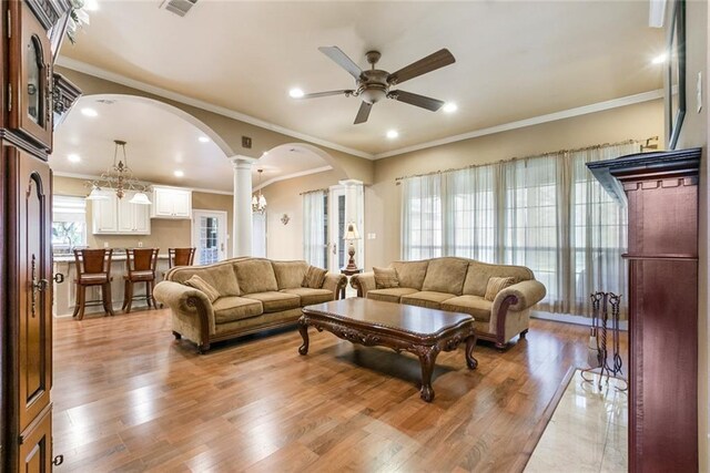 living room with a ceiling fan, decorative columns, arched walkways, light wood finished floors, and recessed lighting