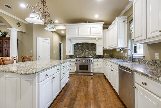 kitchen with a sink, stainless steel appliances, white cabinetry, decorative columns, and visible vents