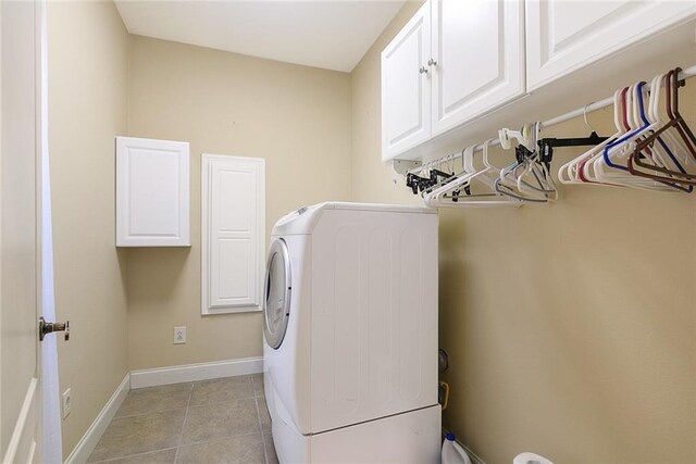 clothes washing area with washer / dryer, light tile patterned floors, baseboards, and cabinet space